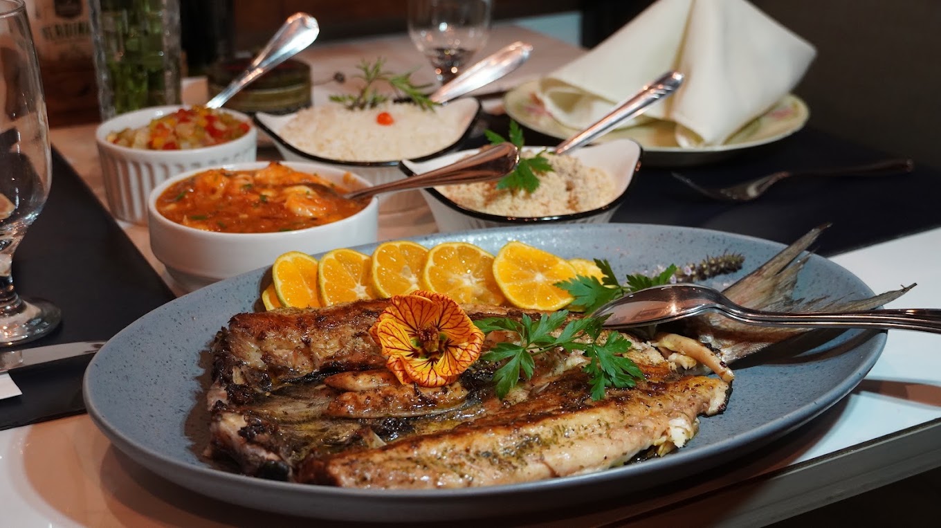 Peixe assado servido com laranjas e acompanhamentos da cozinha da Tasca
